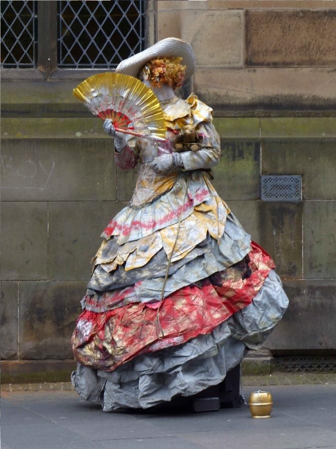 Eine Strassenkünstler Figur in Kleid und mit Fächer
